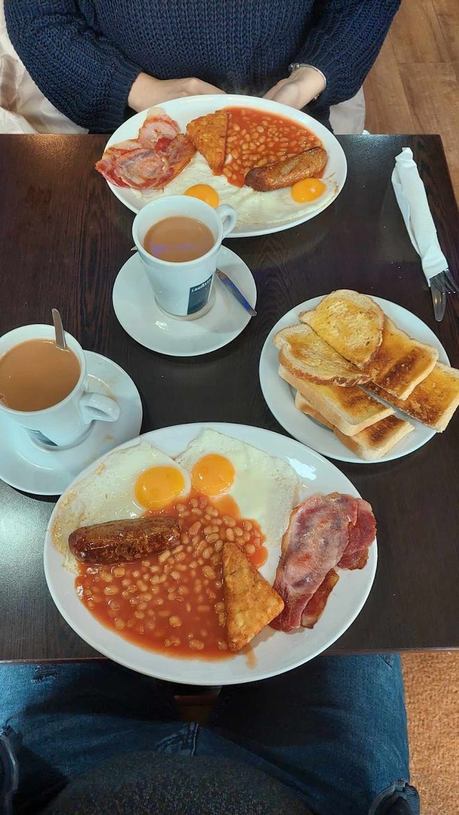 An overhead table set for two with full breakfasts, toast and two cups of tea