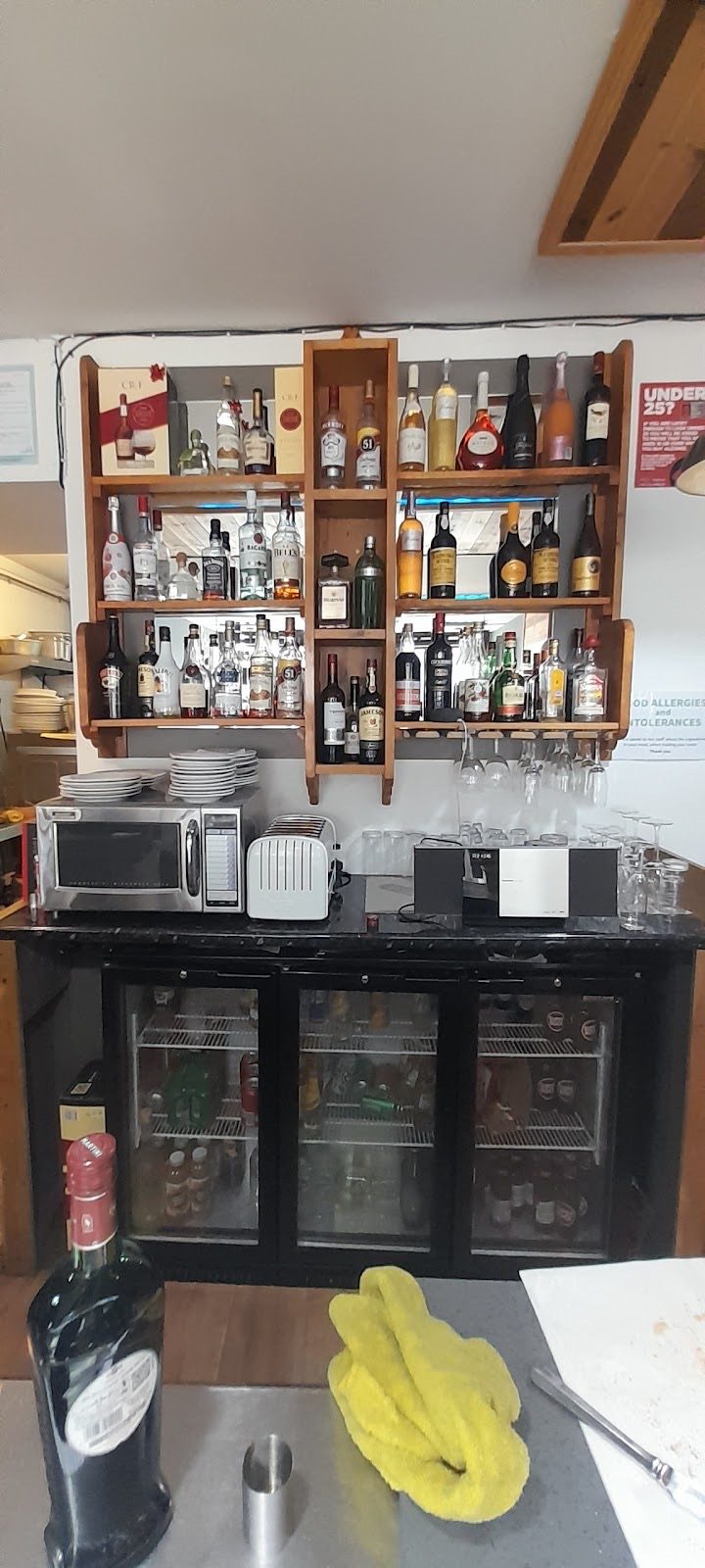 The back counter with the drinks fridge, bottle shelf and a bunch of bananas on the worktop